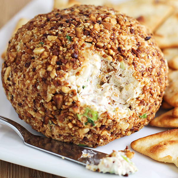 This Pina Colada Cheese Ball recipe is a party food that is sure to be a favorite! Features toasted macadamia nuts, cream cheese, pineapple, green onions, and sweetened flake coconut.
