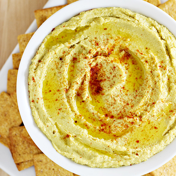 No-Fuss Jalapeno Hummus served in a white bowl, topped with smoked paprika and surrounded by Wheat Thin crackers