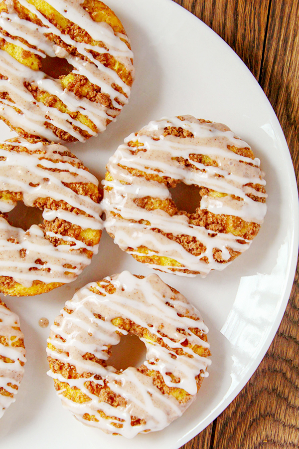 The best of both worlds: cinnamon buns + donuts! This Glazed Cinnamon Bun Baked Donuts recipe is baked in the oven, includes two delicious icings and a cinnamon topping that will make you swoon! These are so good anytime, but especially wonderful with a cup of coffee or for serving to during a special breakfast or brunch.