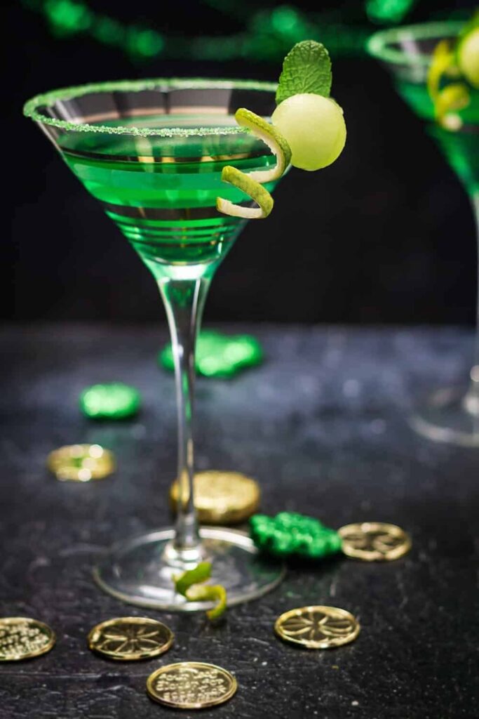 St. Patrick's Day Cocktail in a martini glass with gold coins surrounding it.