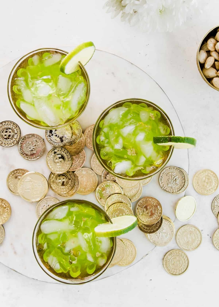 Three glass cups filled with St. Patrick's Day Cocktail with gold coins around the glasses.